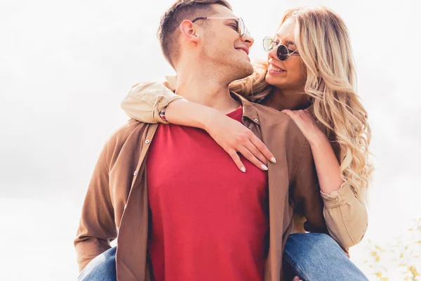 Bonito homem piggybacking seu atraente e loira namorada fora — Fotografia de Stock