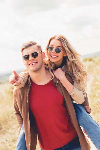 Schöner Mann huckepack seine attraktive und blonde Freundin draußen — Stockfoto