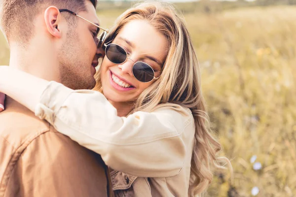 Mujer atractiva abrazos y besos con hombre guapo en gafas de sol - foto de stock