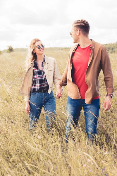 Attraktive Frau und gutaussehender Mann mit Sonnenbrille und Händchen haltend — Stockfoto