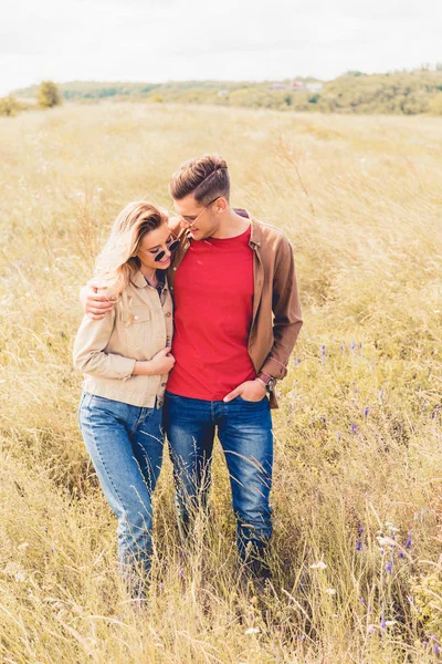 Attrayant femme et bel homme dans des lunettes de soleil étreignant à l'extérieur — Photo de stock