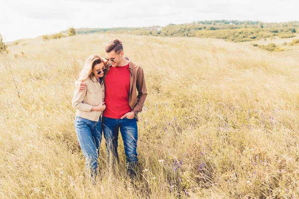 Attraktive Frau und schöner Mann mit Sonnenbrille, die sich draußen umarmen — Stockfoto