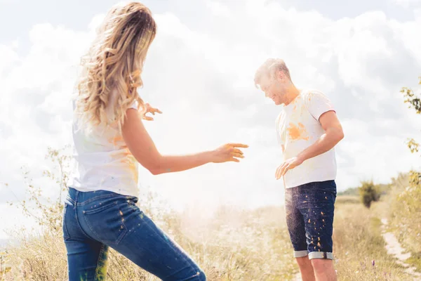 Femme et bel homme en t-shirts jetant de la poudre colorée — Photo de stock