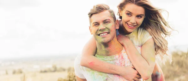 Tiro panorámico de hombre guapo a cuestas a su novia sonriente y atractiva - foto de stock