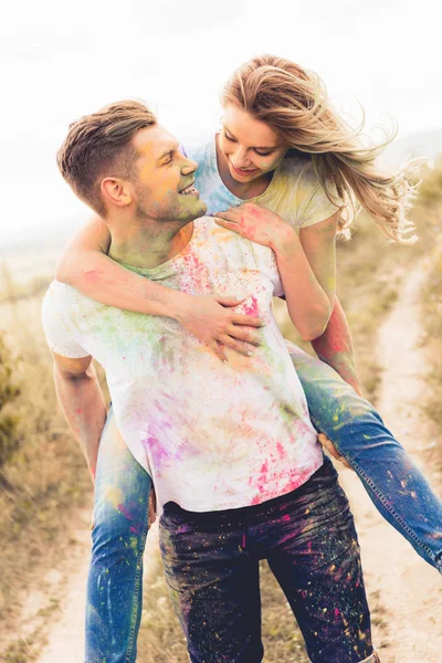 Schöner Mann huckepack seine lächelnde und attraktive Freundin draußen — Stockfoto