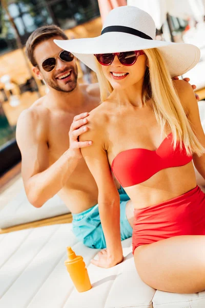 Усміхнений чоловік в сонцезахисних окулярах ніжно торкається подруги на курорті — стокове фото