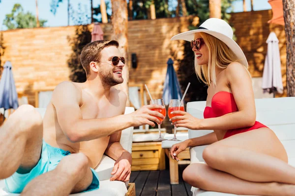 Sexy Paar liegt mit Cocktails auf Liegestühlen im Resort — Stockfoto