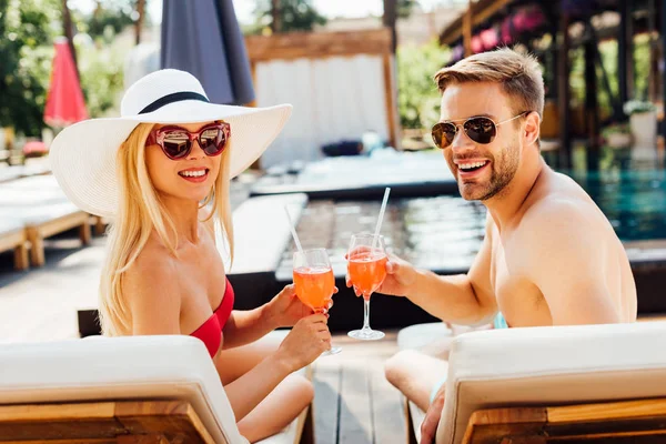 Sexy Paar liegt mit Cocktails auf Liegestühlen im Resort — Stockfoto