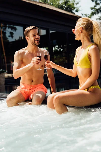 Casal sexy segurando copos de vinho tinto na piscina — Fotografia de Stock