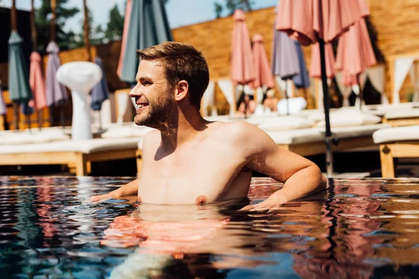 Feliz hombre joven sin camisa en la piscina en el día soleado - foto de stock