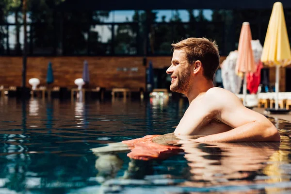 Glücklicher junger Mann ohne Hemd im Schwimmbad bei sonnigem Tag — Stockfoto