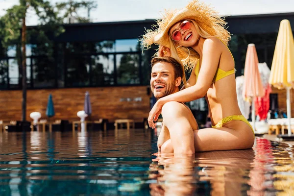 Sexy feliz pareja abrazando en piscina en día soleado - foto de stock