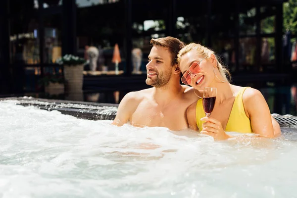 Сексуальная улыбающаяся пара с красным вином в бассейне в солнечный день — стоковое фото