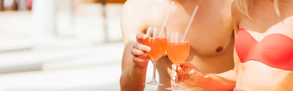 Panoramic shot of sexy couple holding cocktails at resort — Stock Photo