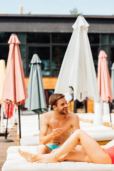 Vue partielle de fille pieds nus et homme torse nu sur des chaises longues à la station — Photo de stock