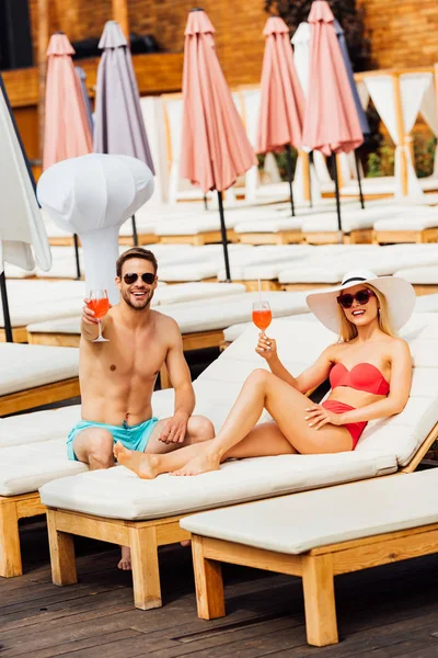 Sexy couple holding glasses of cocktails at resort in sunny day — Stock Photo