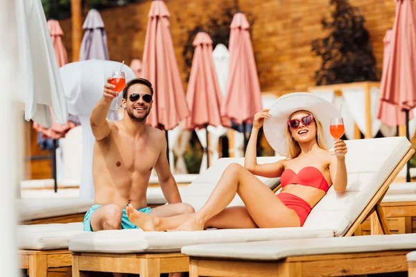Sexy couple holding glasses of cocktails at resort in sunny day — Stock Photo