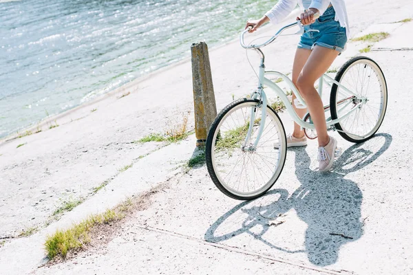 Teilansicht eines Mädchens, das im Sommer in der Nähe des Flusses Fahrrad fährt — Stockfoto