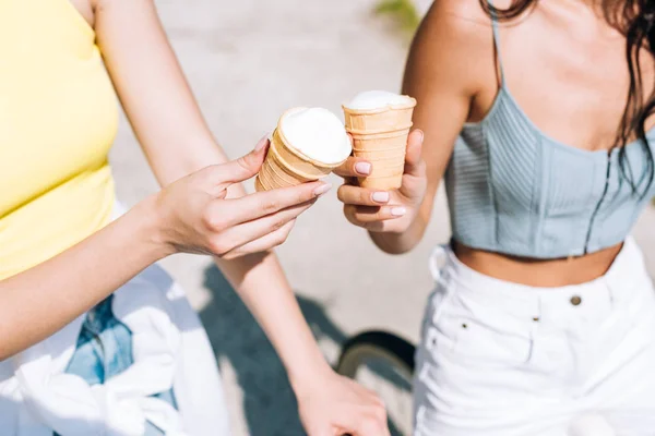 Cropped view of girls riding bikes with ice cream in summer — Stock Photo