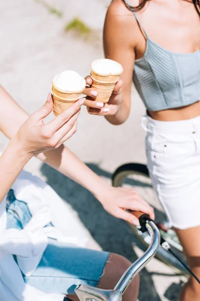 Partial view of girls riding bikes with ice cream in summer — Stock Photo