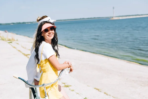 Side view of girls with bicycle near river in summer — Stock Photo