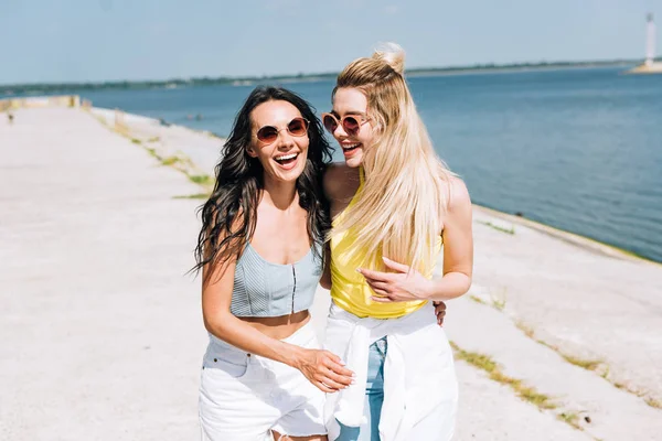 Glücklich lachende Mädchen, die im Sommer am Fluss spazieren gehen — Stockfoto