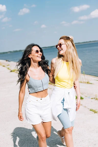 Chicas felices caminando cerca del río en verano - foto de stock