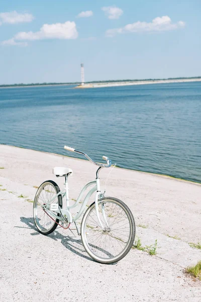 Bicycle on asphalt near blue river in summer in sunshine — Stock Photo