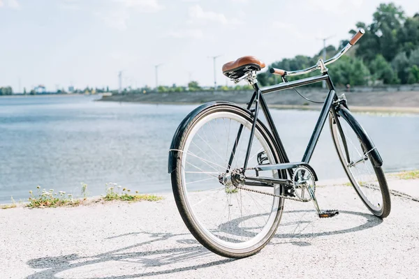 Bicycle near blue river in summer in sunshine — Stock Photo