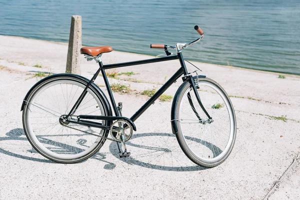 Bicycle near blue pond in summer in sunshine — Stock Photo