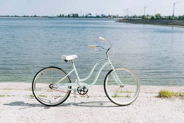 Вид сбоку на велосипед возле синей реки летом в лучах солнца — стоковое фото