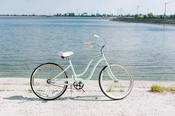 Vista lateral da bicicleta perto do rio azul no verão em sol — Fotografia de Stock