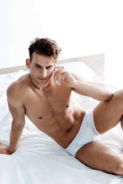 Sexy und hemdlos Mann spricht auf Smartphone im Bett — Stockfoto