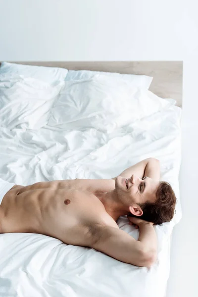 Sexy young man smiling while lying on bed — Stock Photo