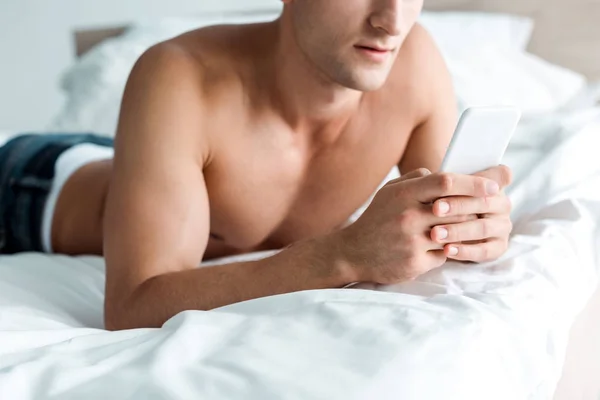 Обрезанный вид человека с помощью смартфона в спальне — стоковое фото