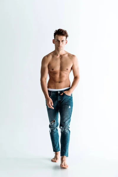 Bel homme en jeans marchant la main dans la poche sur blanc — Photo de stock