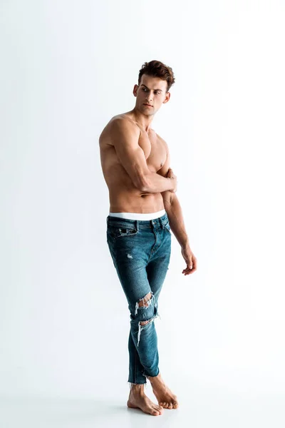 Homme sexy en jeans toucher la main tout en se tenant sur blanc — Photo de stock
