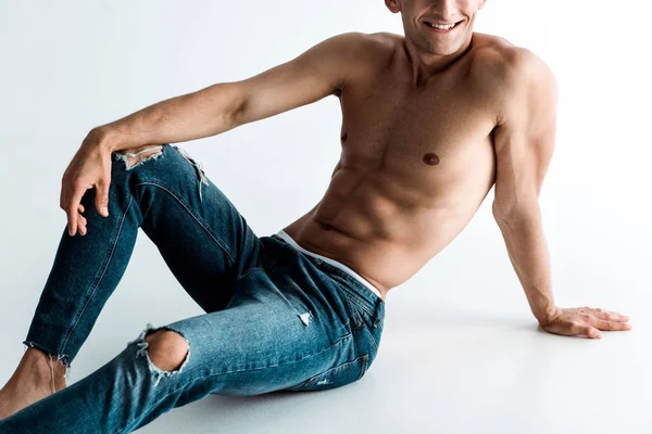 Cropped view of positive and sexy man sitting on white — Stock Photo