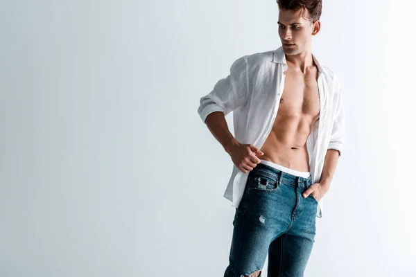 Homme sexy en jeans et chemise debout avec la main dans la poche sur blanc — Photo de stock