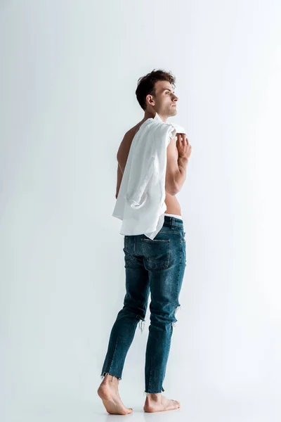 Sexy man in blue jeans holding shirt and standing on white — Stock Photo