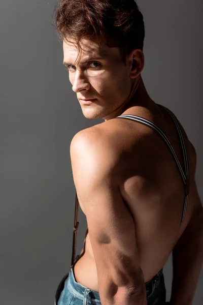 Shirtless man in suspenders looking at camera isolated on grey — Stock Photo