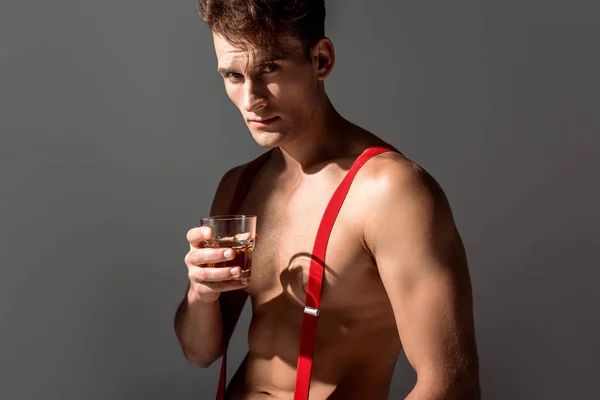 Hombre guapo sosteniendo vidrio con whisky aislado en gris - foto de stock