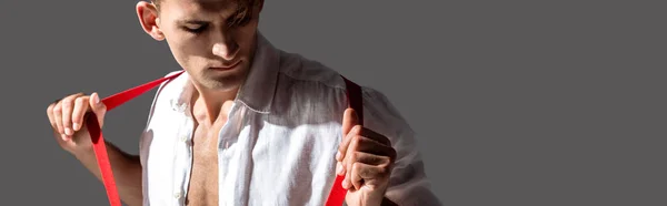 Panoramic shot of man in shirt touching red suspenders isolated on grey — Stock Photo