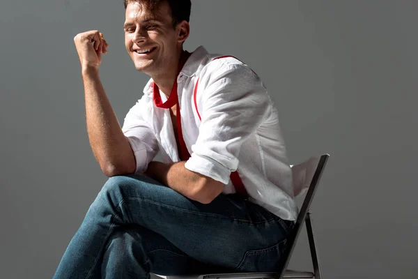 Fröhlicher Mann im weißen Hemd sitzt isoliert auf grau — Stockfoto