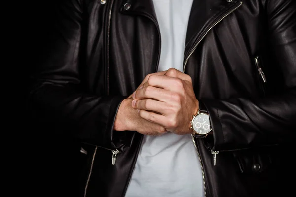 Vista recortada de hombre joven con estilo en chaqueta de cuero con las manos apretadas aisladas en negro - foto de stock