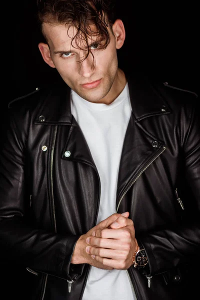 Brutal man in leather jacket with clenched hands isolated on black — Stock Photo