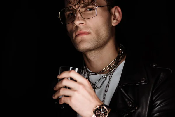 Selective focus of stylish man in eye glasses holding whiskey isolated on black — Stock Photo