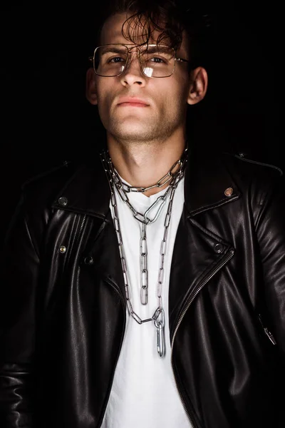 Homme élégant dans des lunettes avec des chaînes sur le cou isolé sur noir — Photo de stock