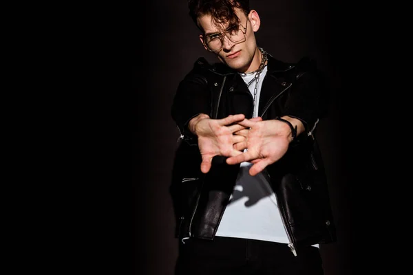 Selektiver Fokus eines jungen Mannes in Brille mit geballten Händen auf Schwarz — Stockfoto