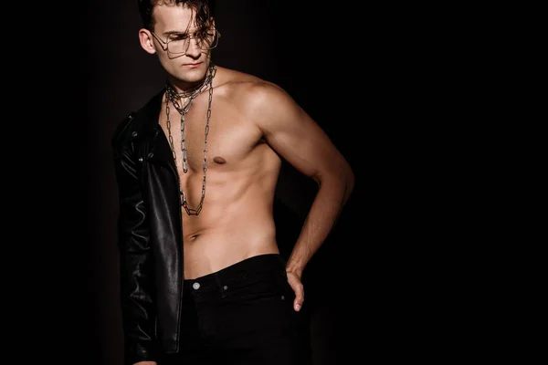 Sexy man with chains on neck standing with hand on hip isolated on black — Stock Photo
